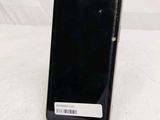 a black cell phone sitting on a stand on a white surface