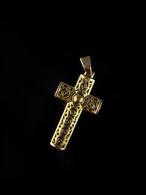 a gold cross pendant on a black background