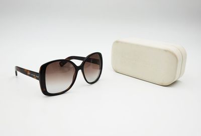 sunglasses and a case on a white surface with a white background