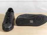black leather sneakers on a wooden table with a white wall in the background