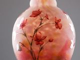 a glass vase with flowers painted on it sitting on a table