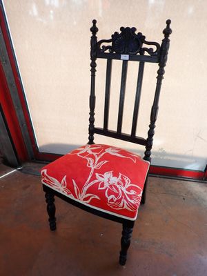 a chair with a red cushion on it in front of a glass door