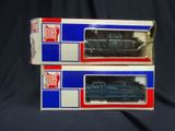 two boxes of toy trains sitting on a black surface