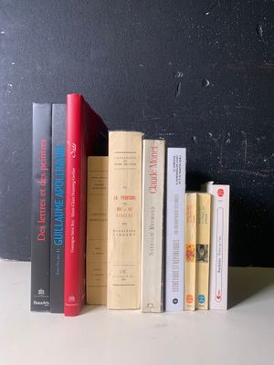 Plusieurs livres sont alignés sur une étagère devant un mur noir