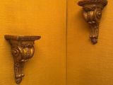 des murs jaunes dans une salle de bains, avec deux supports décorés fixés au mur