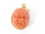 une photo d'un pendentif en forme de visage de couleur corail, monté sur une chaîne plaquée or