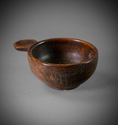 an old wooden bowl with a wooden spoon on a gray surface