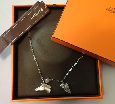 une boîte orange contenant un collier orné d'un chien en argent