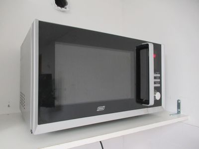 une photo d'un micro-ondes posé sur une étagère dans une cuisine