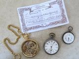 trois montres de poche posées à côté d'un certificat sur une table