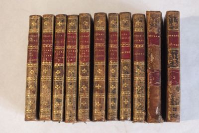 six vieux livres sont alignés sur une surface blanche