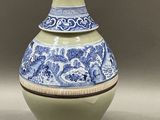 a blue and white vase with a gold top