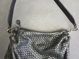 un sac à main gris et noir avec un pompon suspendu à la poignée