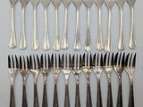 an assortment of forks and spoons arranged in a row on a table