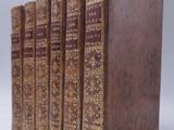 four books are lined up in a row on a white surface
