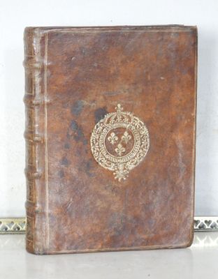 un livre en cuir marron orné d'un emblème doré