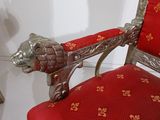 a red and gold chair with a lion head on it