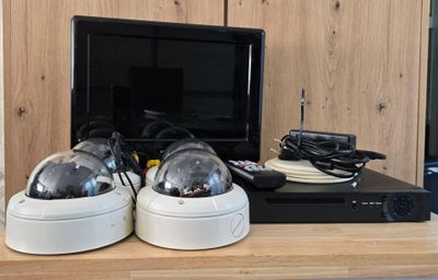 two cameras sitting on top of a desk next to a monitor