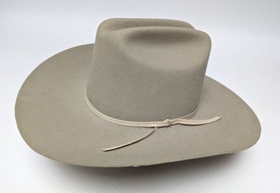 the hat is tan and has a brown ribbon around the brimle
