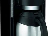 La cafetière est noire et argentée, avec une carafe en verre.