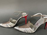 silver and red high heeled shoes on a grey surface