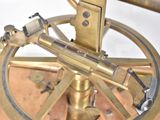 a brass sundial on a wooden stand with a white background