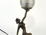 une image représentant une lampe sur laquelle une femme tient une boule de verre