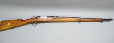 un fusil avec un canon en bois sur une surface blanche
