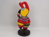 brightly colored ceramic figurine of a woman holding a red object
