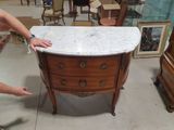 a man that is standing next to a marble top dresser