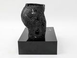 a black vase sitting on a black stand on a white surface