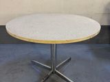 une table blanche avec un plateau en bois posée sur un sol en béton