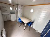 a small room with a table and blue chairs in it