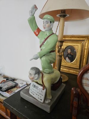 une statue représentant un homme, posée sur une table avec une lampe