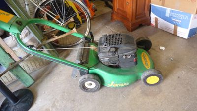 une tondeuse à gazon verte posée par terre à côté d'un vélo