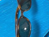 un sac à main bleu sur lequel sont posées une paire de lunettes de soleil