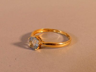 une bague en or sertie d'un diamant, posée sur une table