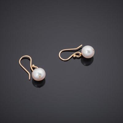 a pair of pearl earrings on a black surface