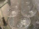 many wine glasses on a glass shelf in a glass case
