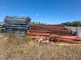 un tas de tuyaux en acier posé dans un champ à côté d'un bâtiment