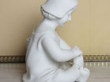 a white statue of a child sitting on a marble floor