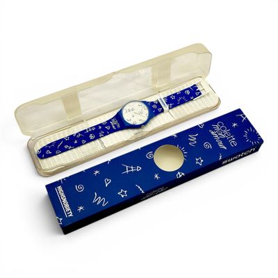 une montre et un stylo dans une boîte posée sur une surface blanche