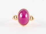 gros plan d'une bague en pierre rose sur une surface blanche