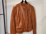une veste en cuir marron suspendue à un porte-manteau dans une pièce