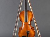 an old violin sitting on top of a stand on a gray surface