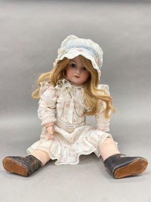 poupée assise par terre, vêtue d'une robe blanche et d'un chapeau