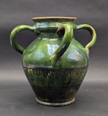 a green vase with two handles sitting on a table