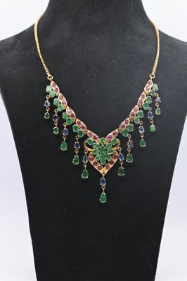un collier composé de pierres multicolores et de chaînes en or, présenté sur un mannequin