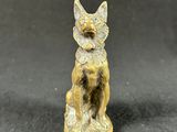 a small figurine of a cat sitting on a black surface