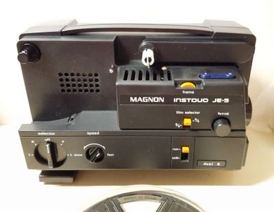 a black film projector sitting on top of a table next to a reel